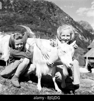 der 1950er Jahre, Stalheim, Norwegen. Eine Fotografie von J Allan Cash von zwei jungen Mädchen umarmt eine Bergziege am Hang. Stockfoto