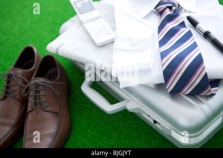 Paar Schuhe und ein T-Shirt neben einem Koffer Stockfoto
