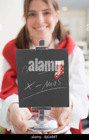 Junge Frau Holding Schiefer mit den Worten Frohe Weihnachten (für Tabelle)- Stockfoto