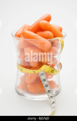 Baby-Karotten in Glas mit Maßband um ihn herum- Stockfoto