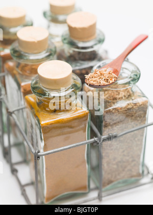Verschiedene Gewürze in kleinen Glasflaschen und auf Löffel- Stockfoto