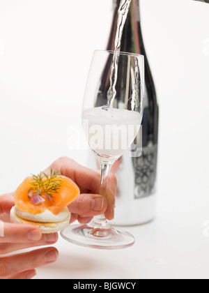 Hände halten Cracker mit Räucherlachs & Glas Prosecco - Stockfoto