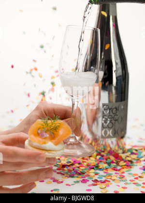 Hände halten Cracker mit Räucherlachs & Glas Prosecco - Stockfoto