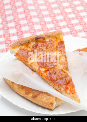 Zwei Scheiben Salami Pizza auf dem Papier- Stockfoto