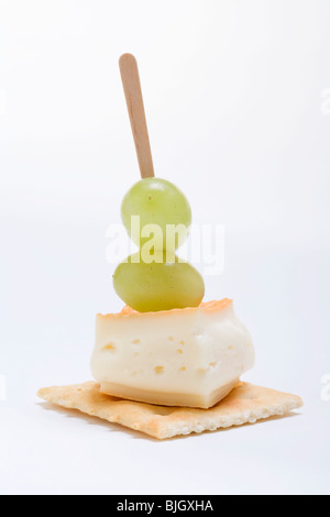 Waschen-Rinde Käse und Trauben auf Cracker- Stockfoto