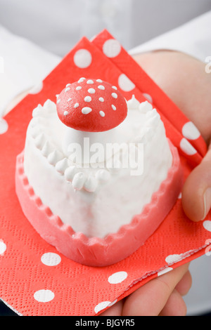 Hände halten kleine Kuchen mit Marzipan fly Agaric- Stockfoto