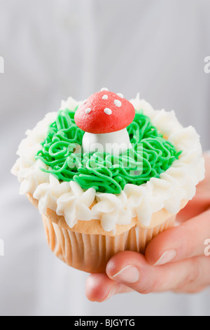 Hand halten Cupcake mit Marzipan-Fliegenpilz- Stockfoto