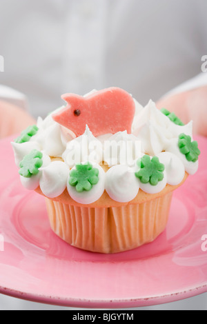 Hände halten Cupcake mit Marzipan Schwein auf rosa Teller- Stockfoto