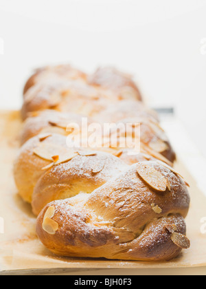 Brot-Zopf mit Flocken Mandeln & Puderzucker auf Backpapier- Stockfoto