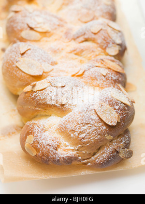 Brot-Zopf mit Flocken Mandeln & Puderzucker auf Backpapier- Stockfoto