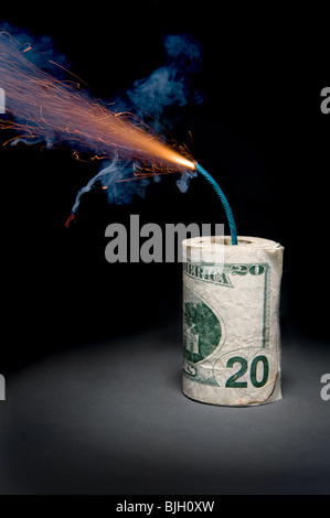 Eine Rolle von Bargeld in einem Dynamit Stick gemacht hat eine beleuchtete Sicherung werfen Rauch und Funken, bevor es explodiert. Stockfoto