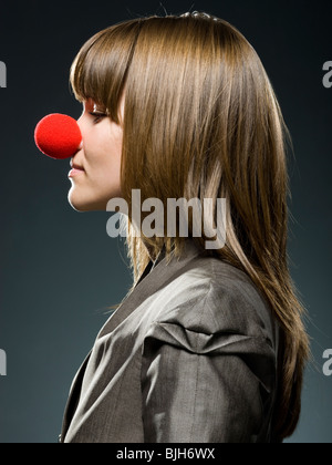 Geschäftsfrau trägt eine rote Clownsnase Stockfoto