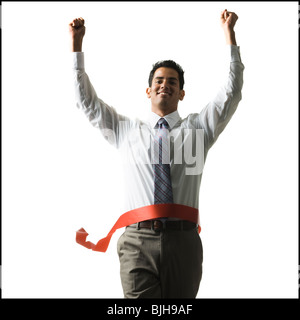 Geschäftsmann, ein Zieleinlauf ein rotes Band mit triumphierend in die Luft erhobenen Armen Stockfoto
