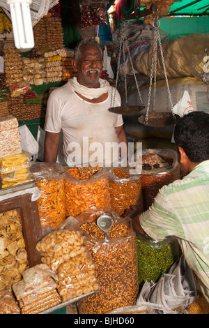 Indien, Kerala, Kanjiramattom Kodikuthu moslemische Festival, snack Stand Mann hinter Säcke mit knusprigen snacks Stockfoto