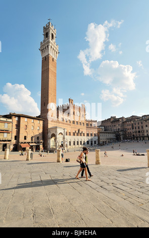 Touristen auf der Piazza del Campo, dem zentralen Platz der Stadt Siena, Toskana, Italien. Torre del Mangia Turm erhebt sich hinter Stockfoto