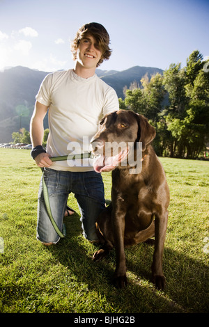 junger Mann kniend mit einem chocolate Labrador retriever Stockfoto