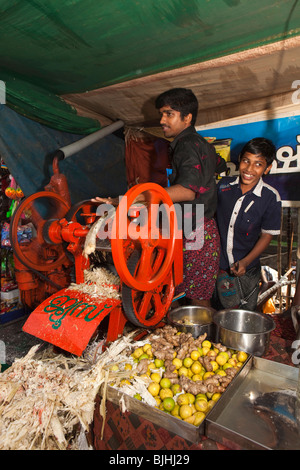 Indien, Kerala, Kanjiramattom Kodikuthu moslemische Festival, drücken Männer Betrieb Zuckerrohr an kalte Getränke Stand Stockfoto