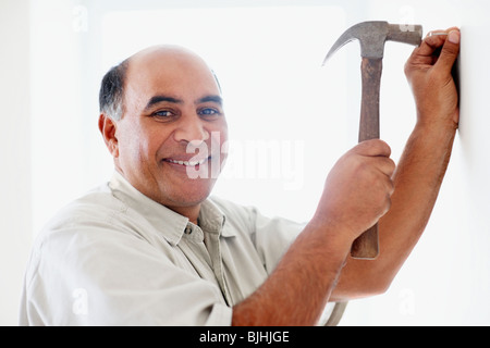 Mann Hämmern Nagel in Wand Stockfoto