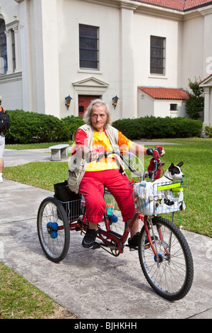 Ältere Frau mit drei Rädern Fahrrad mit Hund im Korb an The Cathedral Basilica Saint Augustine in Florida Stockfoto