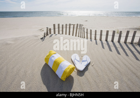 Handtuch und Flip Flops am Strand Stockfoto