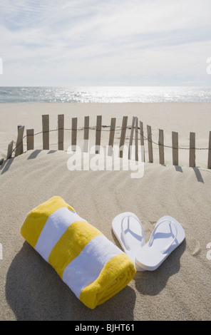 Handtuch und Flip Flops am Strand Stockfoto