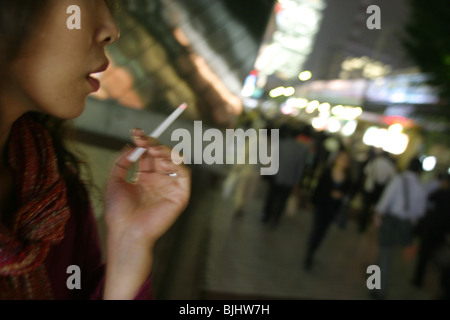 Stilvolle, modische Frau Rauchen Zigarette in Tokio Straße, Japan. Stockfoto
