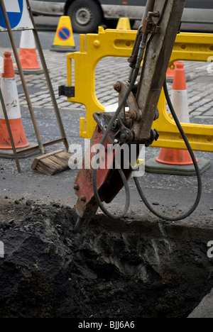 Hydraulisches Bohrgerät-Anlage auf einem Bagger graben ein Loch in der Straße. Stockfoto