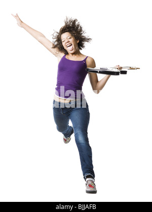 Mädchen mit Zahnspange und Gitarre springen und Zunge heraus Stockfoto