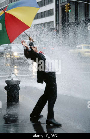 Geschäftsmann unter einem Brolly-Treffer von Spritzwasser, NYC, USA, 1990er Jahre Stockfoto