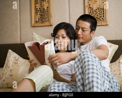 Paar im Bett kuscheln und lesen Stockfoto