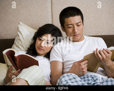 Paar im Bett kuscheln und lesen Stockfoto