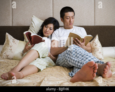 Paar im Bett kuscheln und lesen Stockfoto