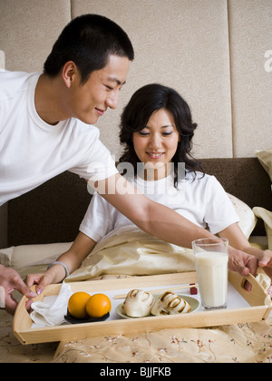 Mann Frau Frühstück im Bett zu bringen Stockfoto