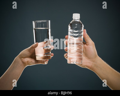 Glas Wasser hält die Hand und hand halten Wasser in Flaschen Stockfoto