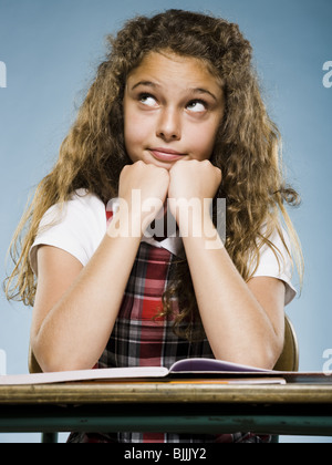 Mädchen mit Arbeitsmappe suchen am Schreibtisch sitzen gelangweilt Stockfoto