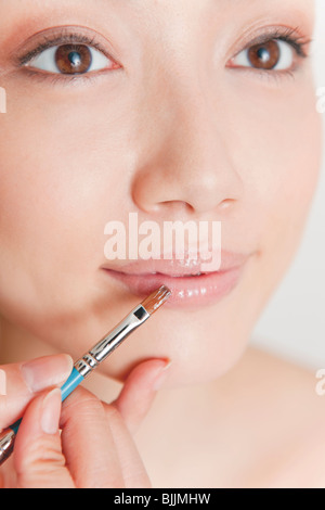 Junge Frau Auftragen von Lippenstift Stockfoto
