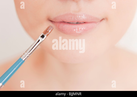 Junge Frau Auftragen von Lippenstift Stockfoto