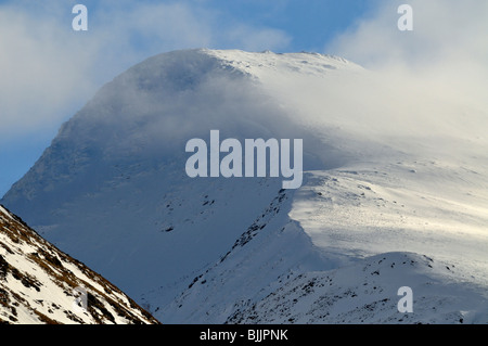 Nebel und Cloud hängt um den abgerundeten Gipfel eines schneebedeckten Berges Stockfoto