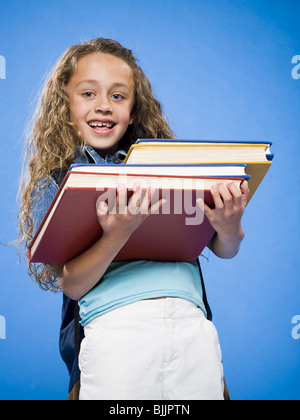 Lächelndes Mädchen mit Rucksack Haufen Lehrbücher Stockfoto