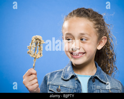 Profil von Mädchen lecken Teig aus Schlegel Stockfoto