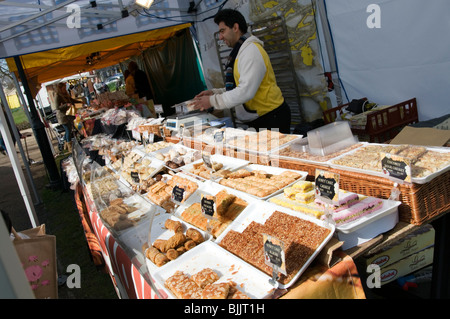 Ein Verkäufer auf einen Stall mit süßem Gebäck auf einem französischen Markt in England Stockfoto