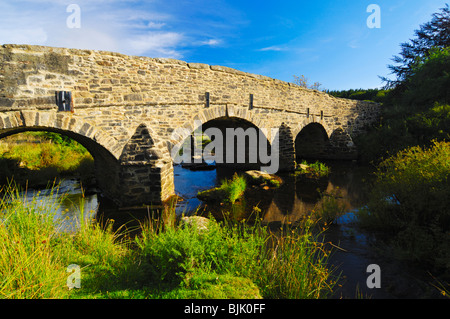 Brücke über den East Dart River bei Postbridge in Dartmoor Devon, England. Die alten clapper Bridge hinter der Brücke kann durch die Bögen der Brücke gesehen werden. Stockfoto
