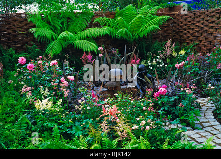 Eine kleine städtische Innengarten mit Baumfarnen und bunte Blumen Stockfoto