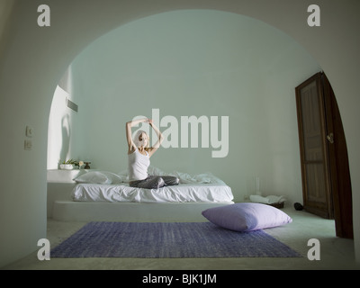 Frau sitzt auf dem Bett ausdehnen Stockfoto