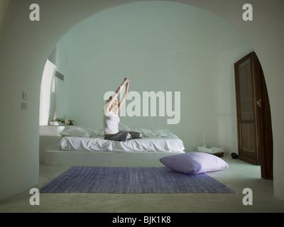 Frau sitzt auf dem Bett ausdehnen Stockfoto