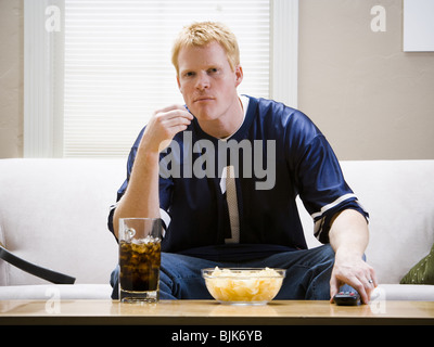 Mann mit riesigen Handschuh und Getränke auf Sofa lächelnd und jubeln Stockfoto