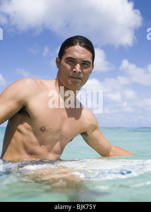 Mann sitzt auf Surfbrett im Wasser lächelnd Stockfoto