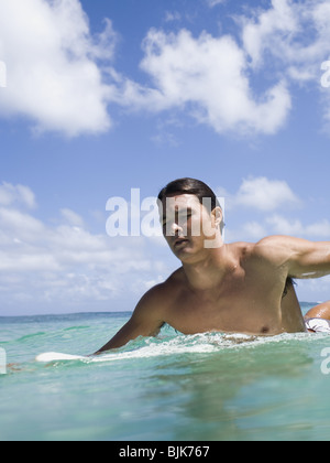 Mann sitzt auf Surfbrett im Wasser lächelnd Stockfoto