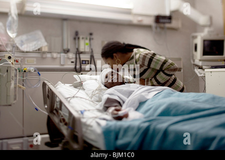 Mutter küssen Junge im Krankenhausbett mit Kopf-Bandagen Stockfoto