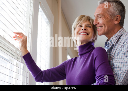 Älteres Paar auf der Suche durch Jalousien Stockfoto